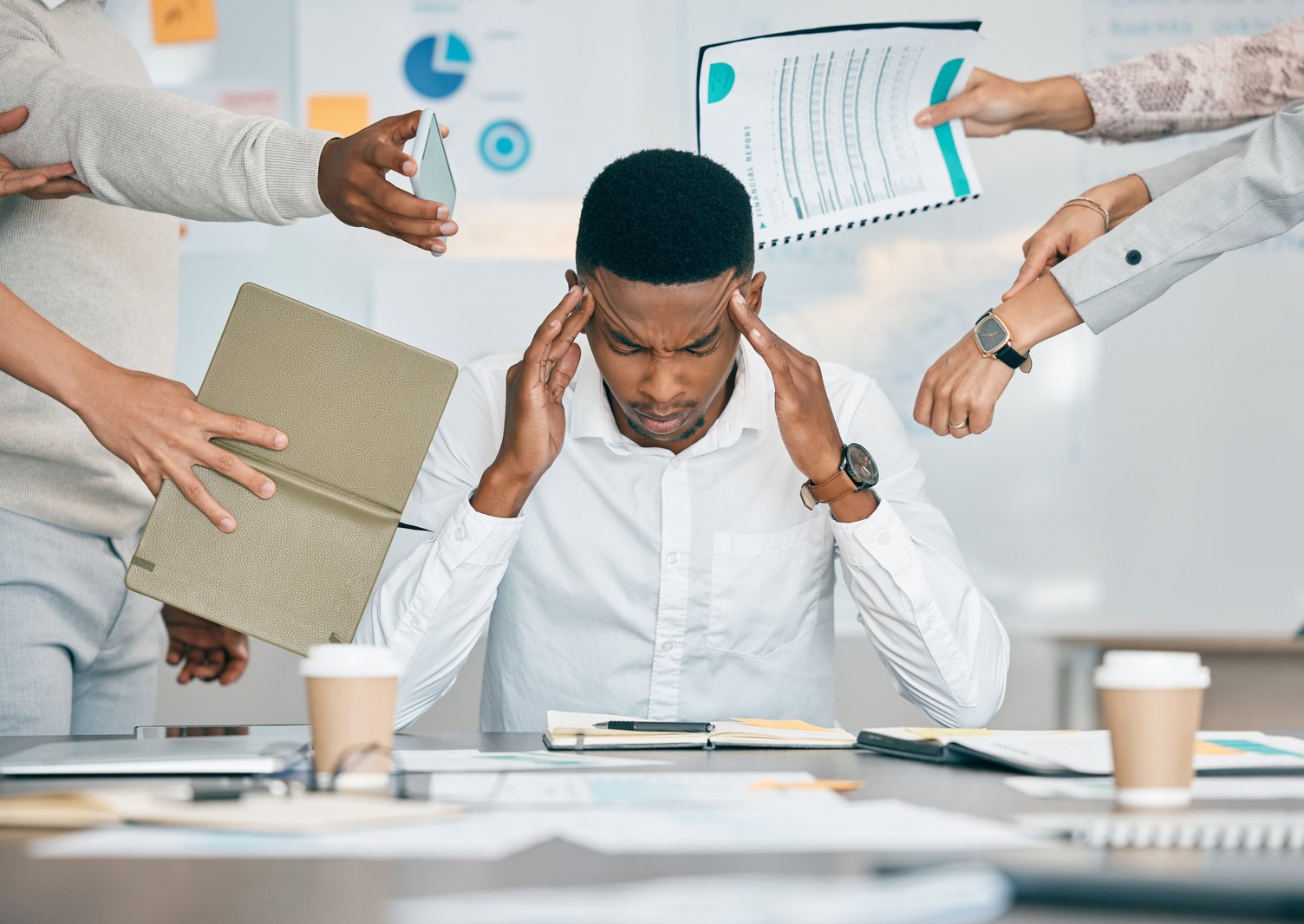 Stress, Burnout and Tired Black Man with Headache, Frustrated or Overwhelmed by Coworkers at Workplace. Overworked, Mental Health and Anxiety of Exhausted Male Worker Multitasking at Desk in Office.